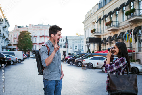 Young mixed race tourist couple taking pictures on vintage camera while walking through the city