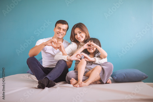 Portrait Happy Asian Family making heart shape in bedroom.