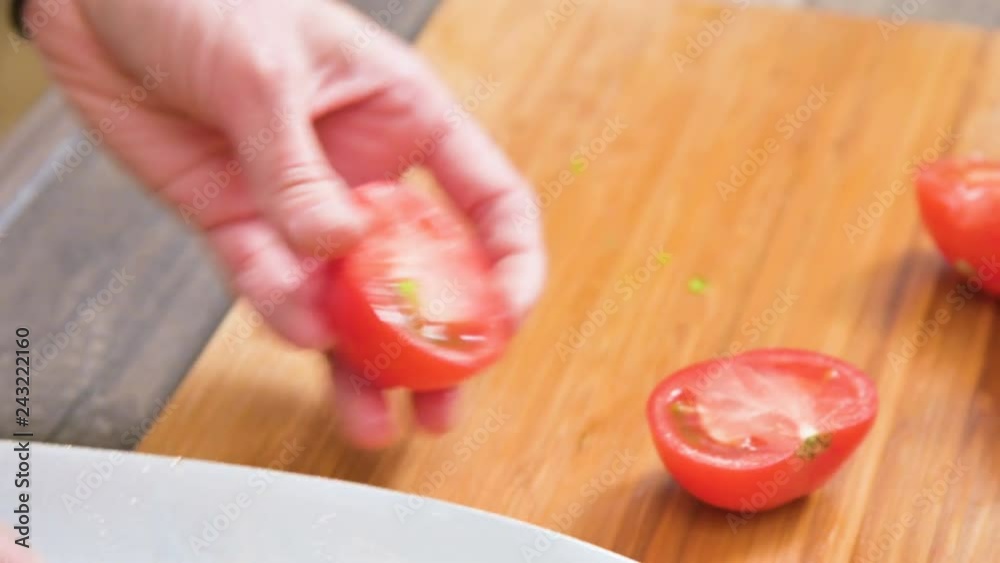Close-up of female hands with a knife are cutting tomatoes for making salad on a wooden cutting board. Home kitchen. Healthy food Close-up of female hands with a knife are cutting tomatoes for making salad on a wooden cutting board. Home kitchen. Healthy food