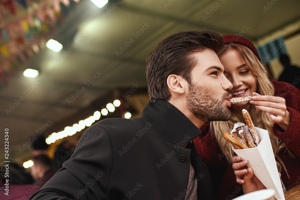 Φωτογραφία Close-up of young couple are eating churros at the street food market