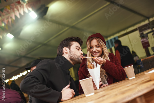 Close-up of young couple are eating churros at the street food market.