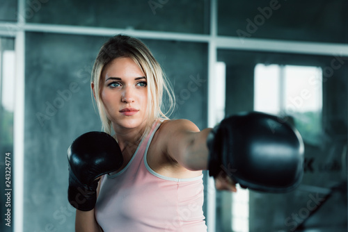 Female boxer is training punching in fitness gym.,Portrait of boxing woman is practicing footwork in sportswear and boxing gloves.,Beautiful of caucasian girl doing exercise punching with concentrate. © Maha Heang 245789