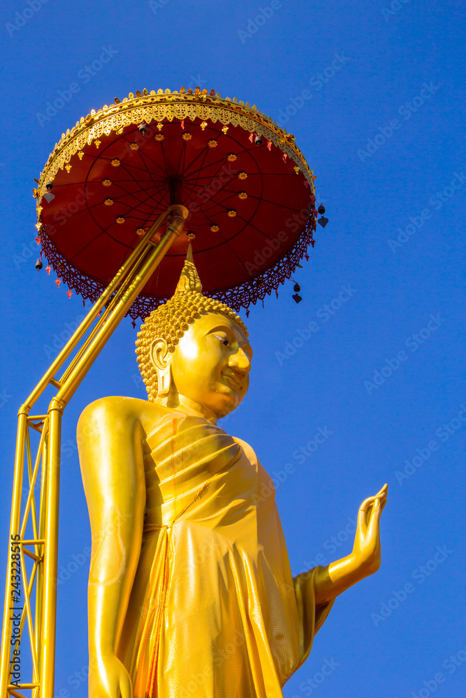 Obraz premium Golden Buddha Standing with golden umbrella with clear blue sky background.