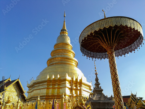 Golden pagoda and the golden umbrella with blue sky background.