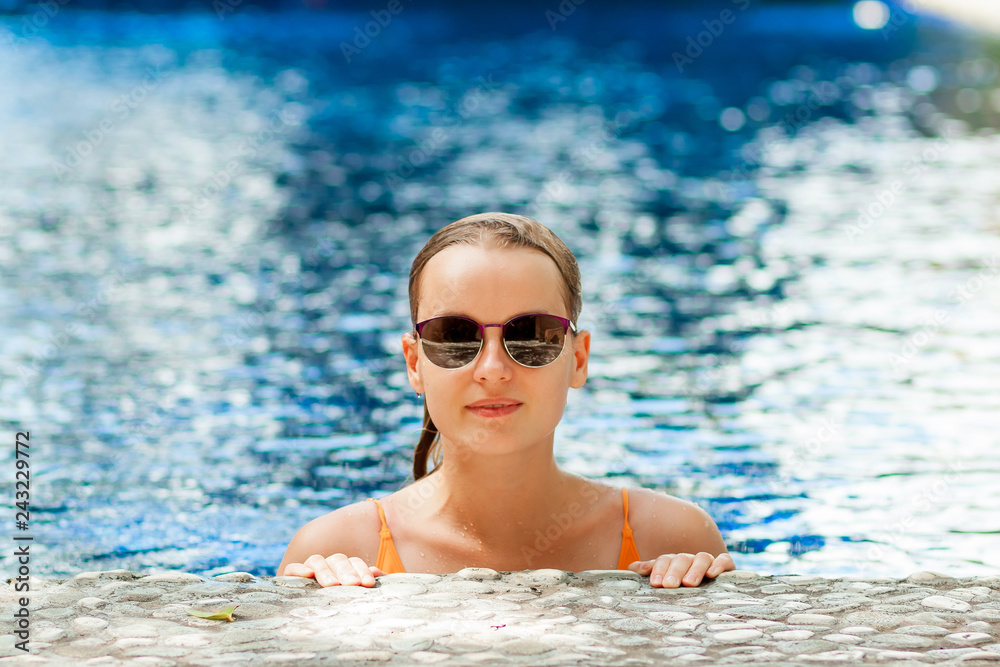 Girl with sunglasses resting at the side of the pool