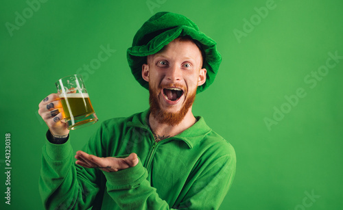 Patricks day party. Portrait of excited man holding glass of beer on St Patrick's day isolated on green. Man in Patrick's suit smiling. photo