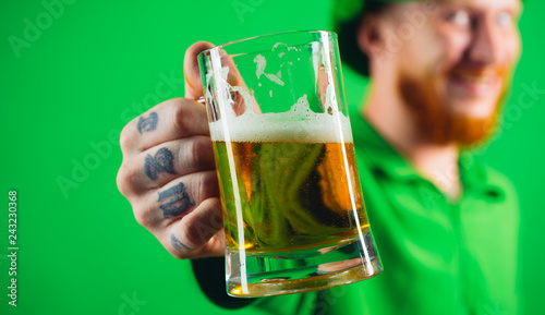 Portrait of excited man holding glass of beer on St Patrick's day isolated on green. photo