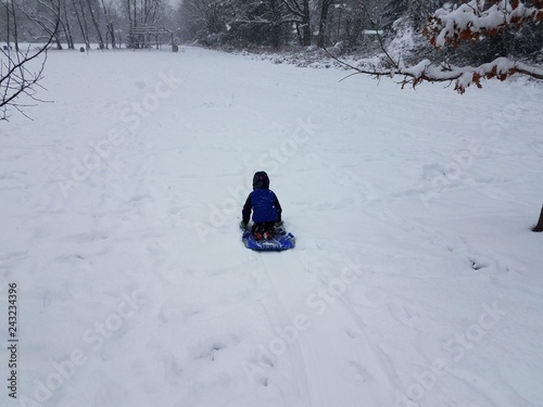 child in blue coat on sled in white snow