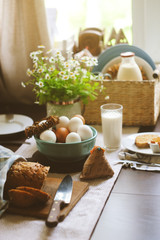 country breakfast on rustic home kitchen with farm eggs, butter, wholegrain bread and milk. Organic homemade food, easter concept.