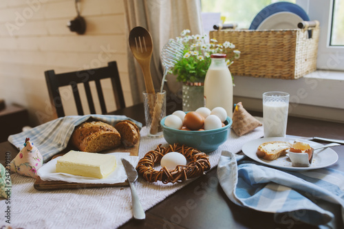 Canvastavla country breakfast on rustic home kitchen with farm eggs, butter, wholegrain bread and milk