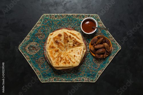 Arabic Cheese Bread with dates on a black table.