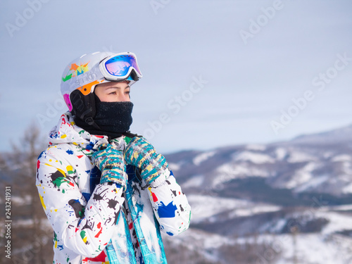 girl holding skis in her hands Happy girl holding skis and ski poles in hands, sitting in snow