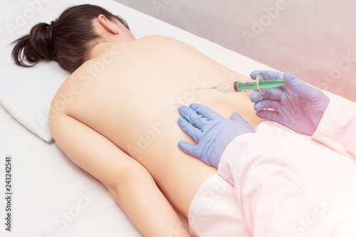 The doctor makes a patient a girl an injection of a blockage in the spine to eliminate back pain, an injection with chondroprotekrom, treatment of the spine, inflammation photo