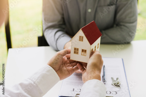 Home agents are giving house gifts to new home buyers in office room.