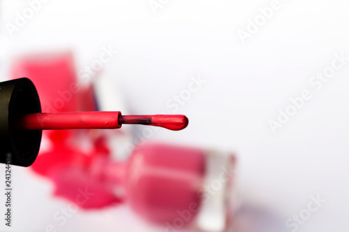 red spilled nail polish and brush for nail polish, on white background 