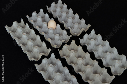 Six egg boxes with one hen egg on a black mat background