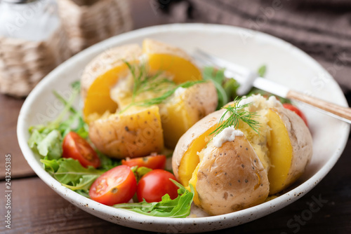 Fotografie Baked stuffed potatoes with cheese, sour cream and dill on a plate