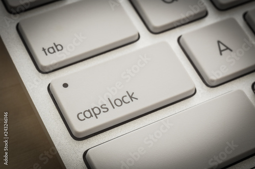 Caps lock button on white keyboard, dark filter. photo