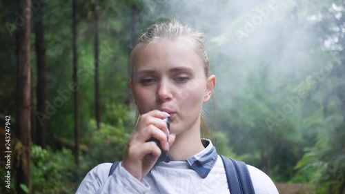 girl uses electronic cigarettes in a beautiful green forest photo