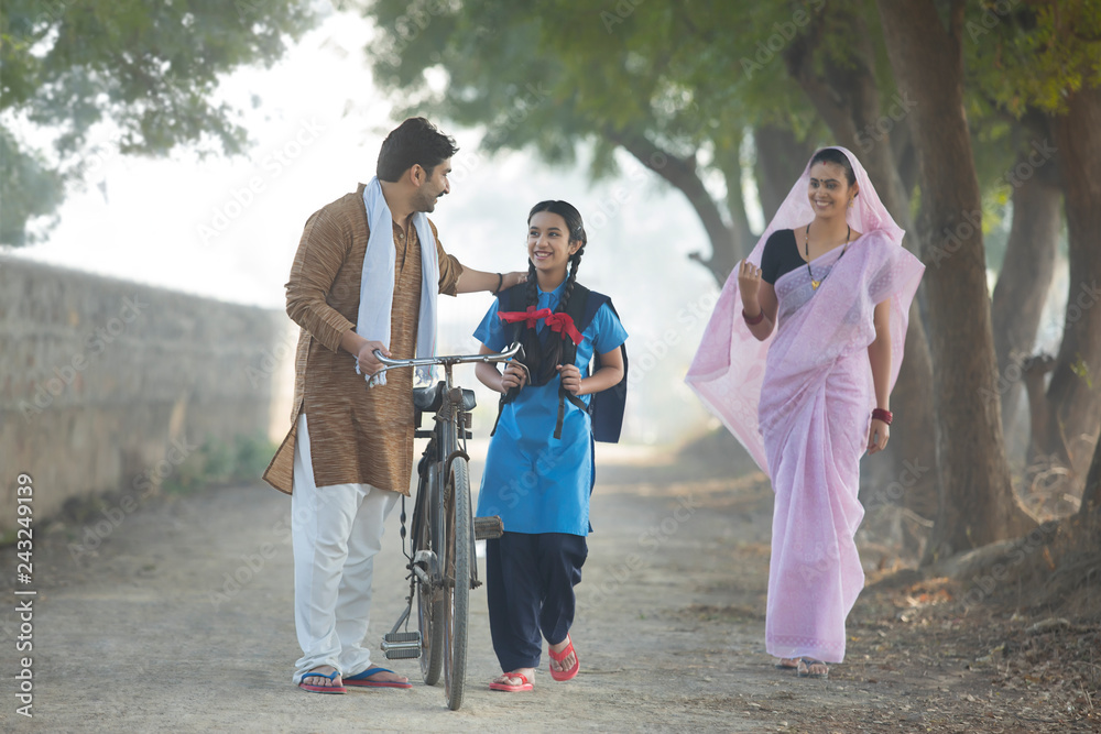 Happy rural family consisting of man, woman and a school going girl walking on street in village. Happy rural family consisting of man, woman and a school going girl walking on street in village.