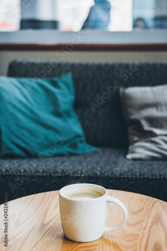 Coffee cup on sofa pillow with cafe interior background