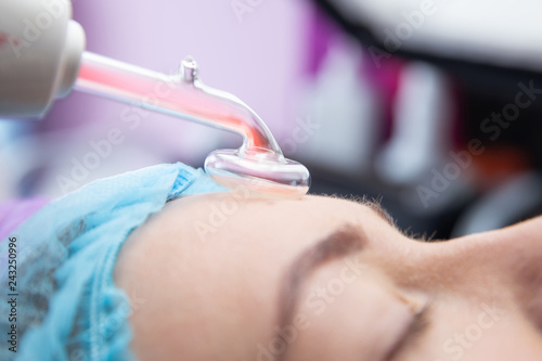 Receiving electric darsonval facial massage procedure at beauty salon photo