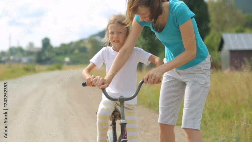 Woman teaching little girl to ride a bicycle Woman teaching little girl to ride a bicycle