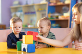 adorable kids boys playing with block toys on table in kindergarten