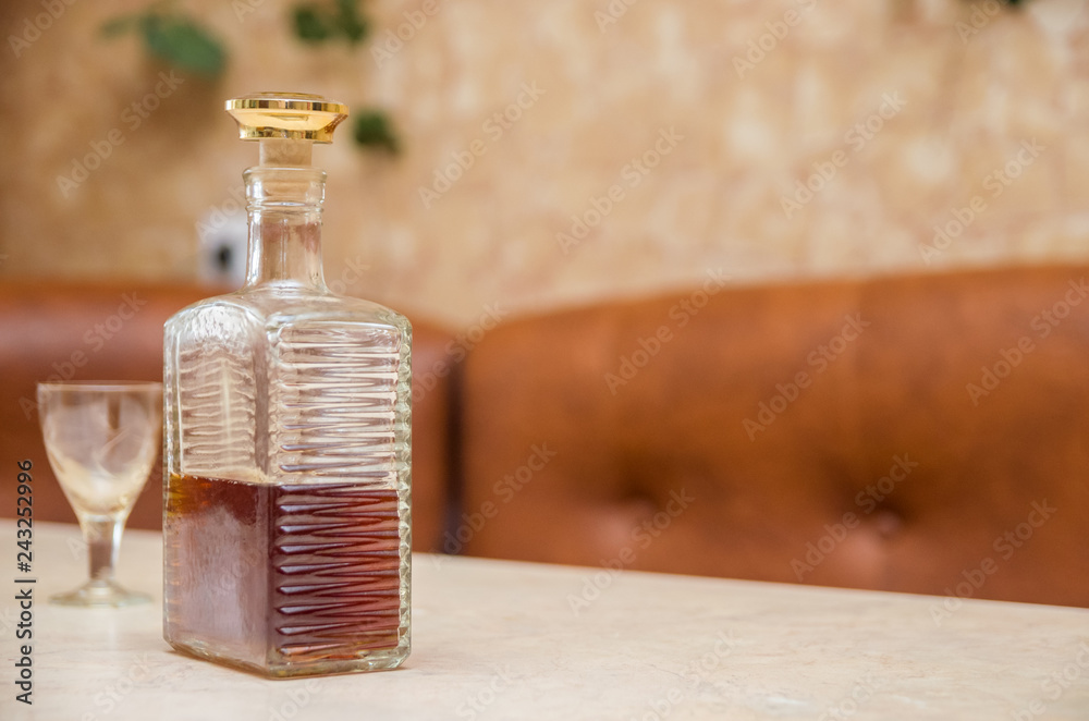 Bottle of cognac, a glass on a wooden table