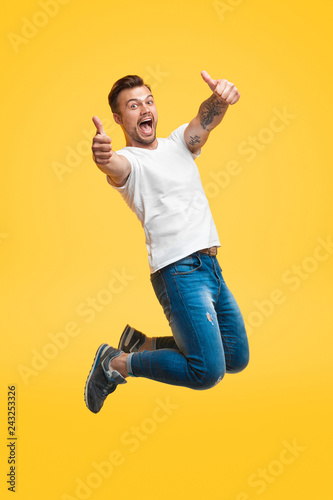 Excited man jumping and gesturing thumb up photo