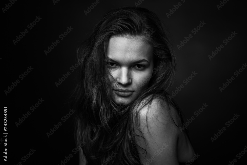 Dramatic black and white portrait of a beautiful girl on a dark background