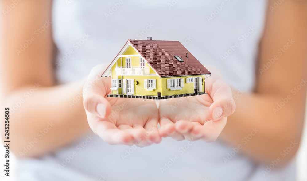 Hands of young woman holding model house Hands of young woman holding model house