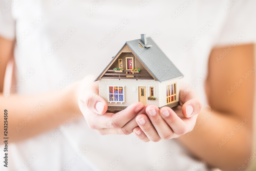 Hands of young woman holding model house Hands of young woman holding model house
