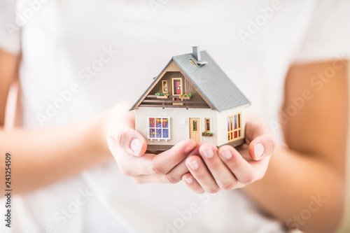 Hands of young woman holding model house