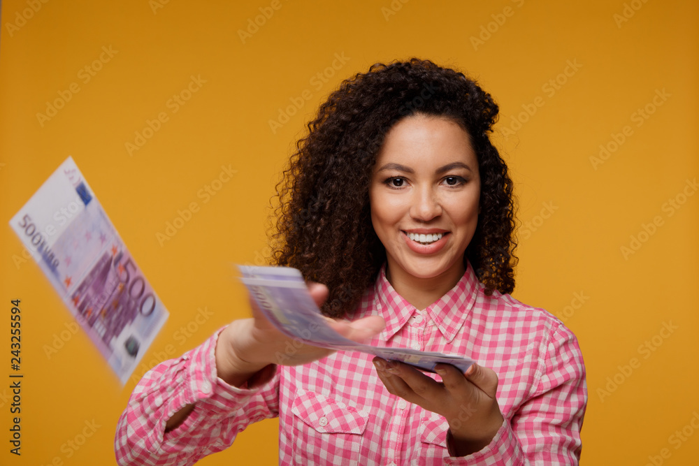 Portrait of an excited young african holding money banknotes and celebrating isolated over yellow background Portrait of an excited young african holding money banknotes and celebrating isolated over yellow background