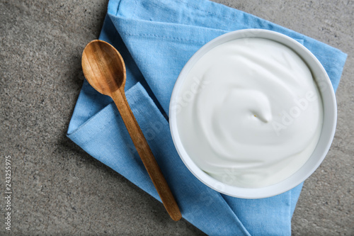 Bowl with tasty yogurt on grey background