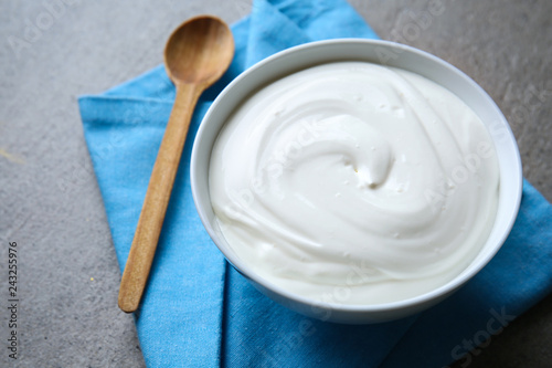 Bowl with tasty yogurt on grey background
