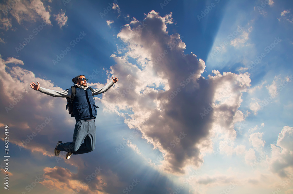 Young man jumping on top of a mountain against the sky