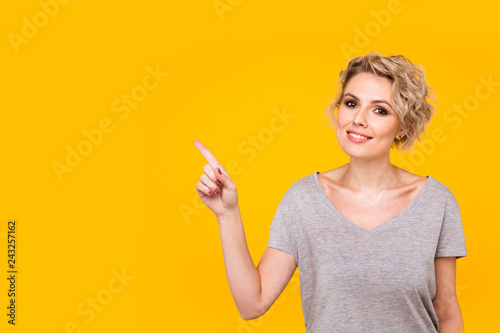 Model pointing upwards in studio and looking at camera. isolated orange background