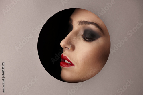 Beauty portreai of a woman with gorgeus makeup thwough circle in gray background photo