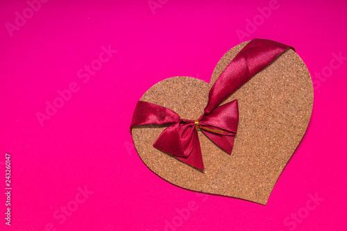 cork heart with red ribbon on it laying on pink background as a symbolof Valentines Day  photo