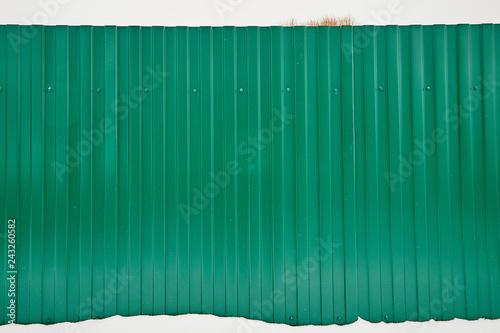 Aluminum fence. Corrugated metal profiled panel. Background of green metal siding, corrugated iron sheet for decoration