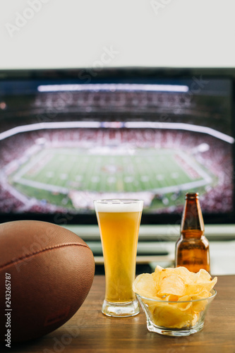 Beer and snacks prepared for watching american football on TV