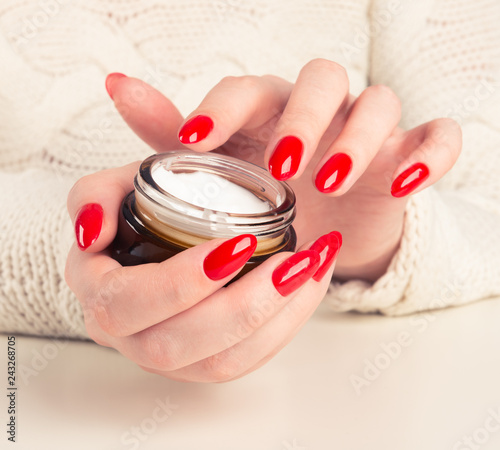 female hands with the jar of cream on white