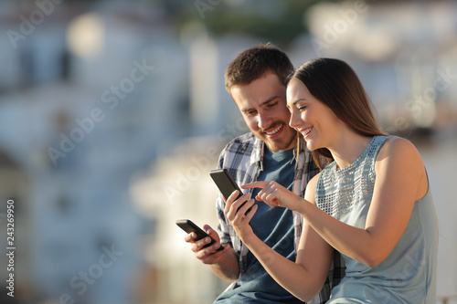 Happy couple sharing phone content in a town