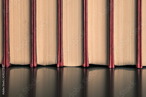 old books with yellowed paper in a red cover on black stage 