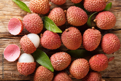 Fresh lychee and peeled showing the red skin and white flesh with green leaf. Horizontal top view
