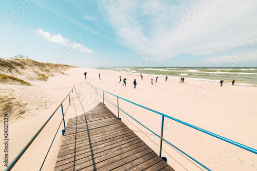 staircase leads to a wide sandy beach  tourists on the shores of the picturesque sea on a beautiful and windy summer day.