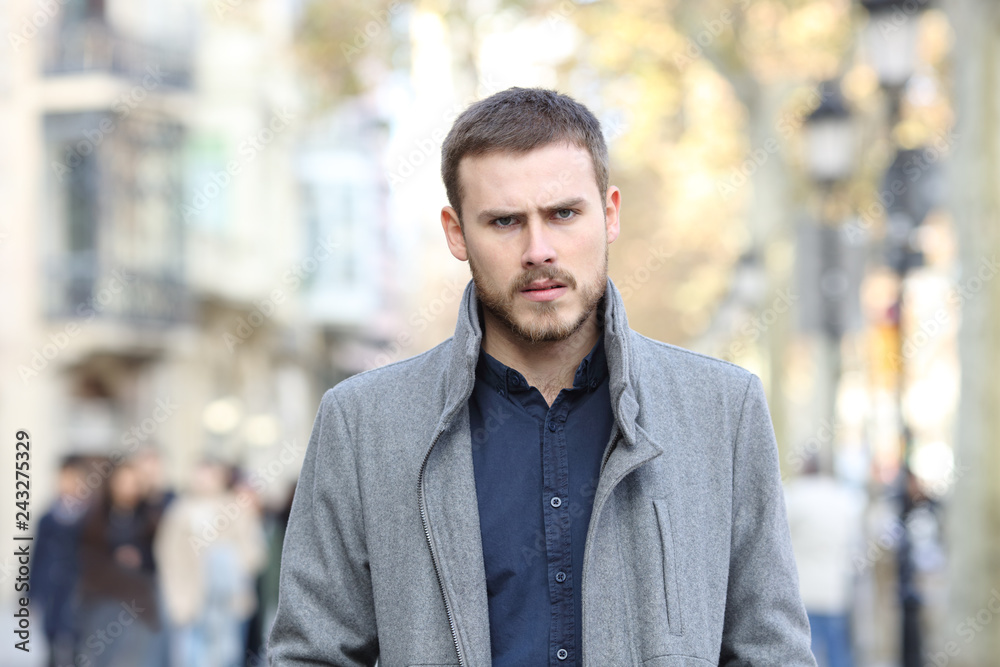 Naklejka premium Angry man walking in the street looking at camera