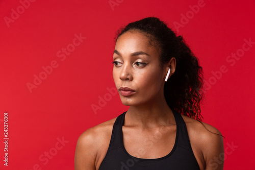 Beautiful young african sports fitness woman posing isolated over red wall background.